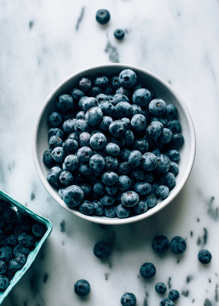 An overhead shot of blueberries in a white bowl.