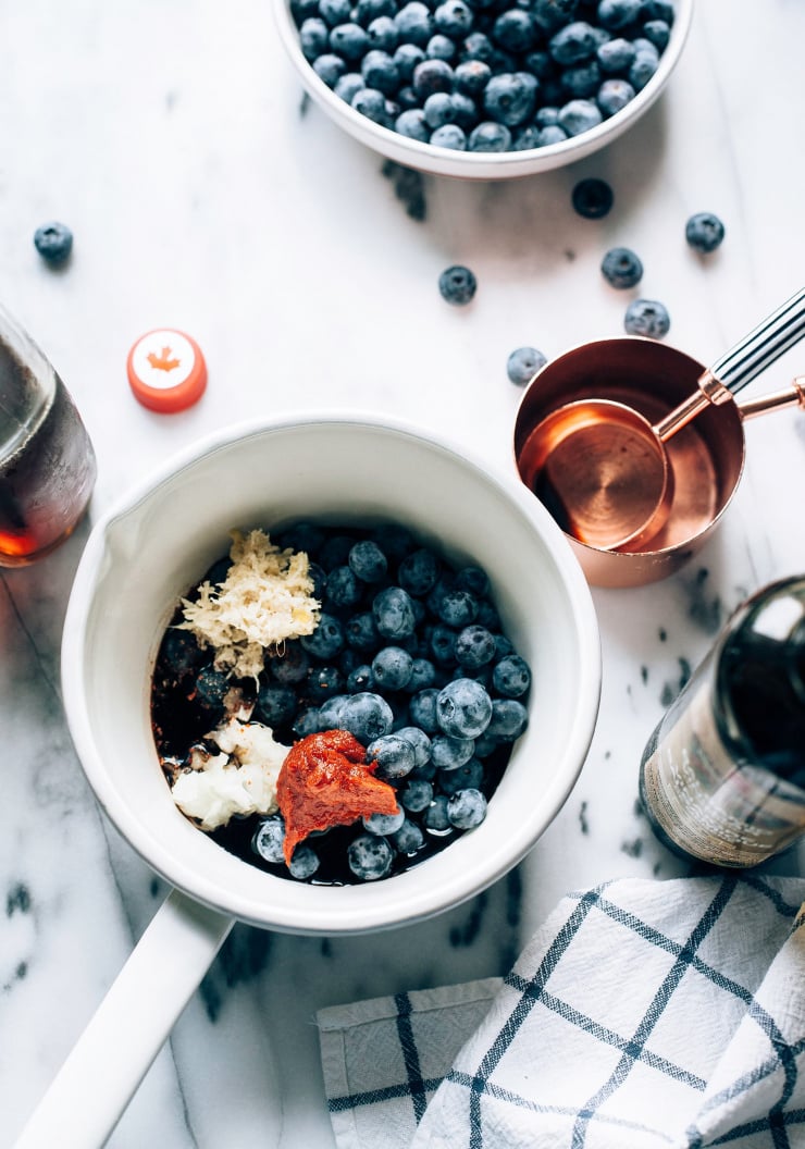 An overhead shot of blueberry bbq sauce being made in a white enamelware saucepan.