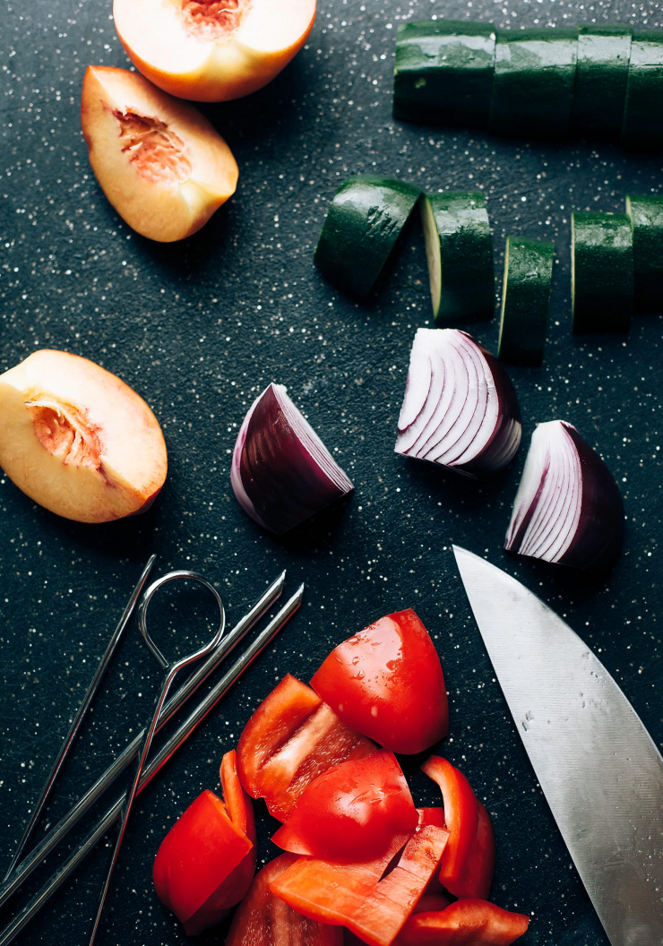 An overhead shot of vegetable skewers being assembled on a black cutting board.