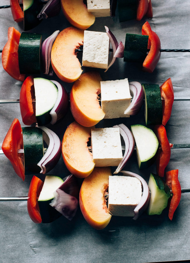 An overhead shot of assembled tofu and vegetable skewers before grilling.