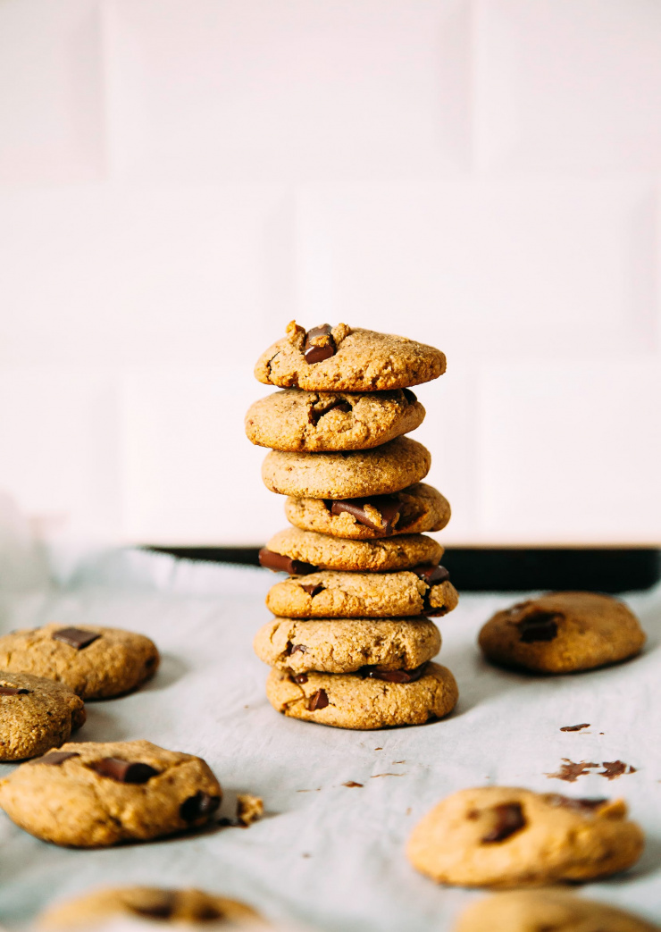 A side angle shot of chocolate chip cookies piled on top of each other against a white background,