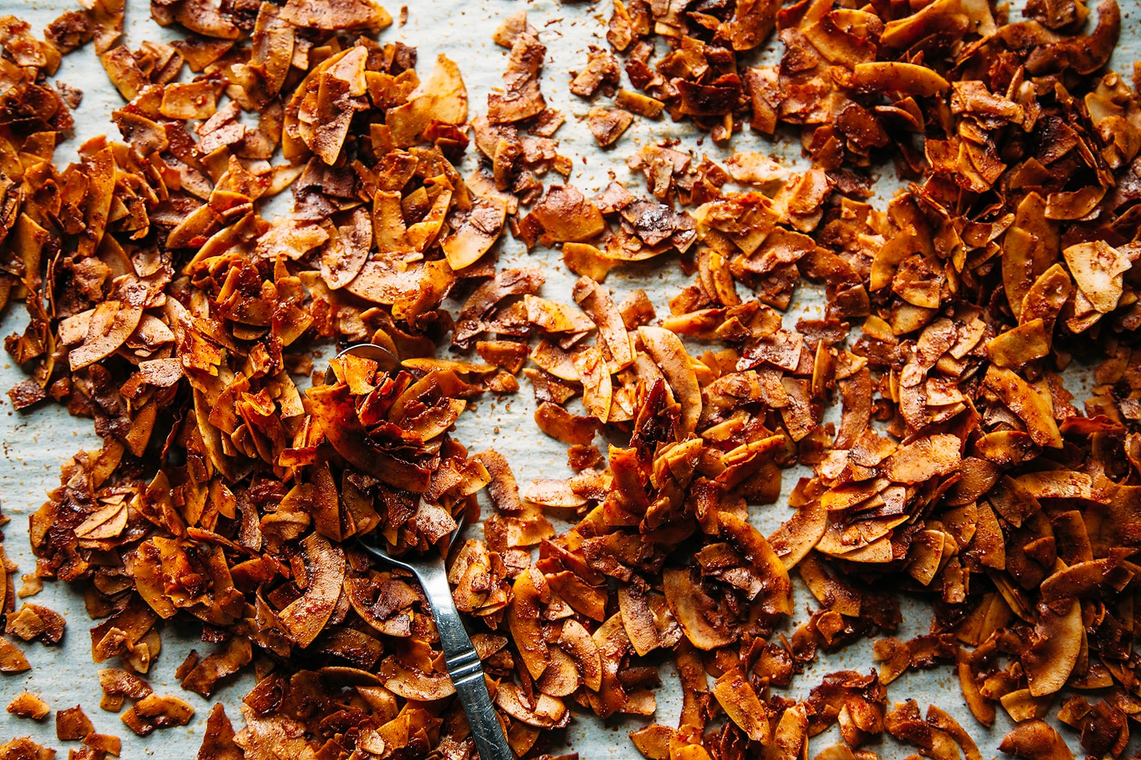 An overhead shot of a sheet pan filled with crispy, browned pieces of coconut "bacon"