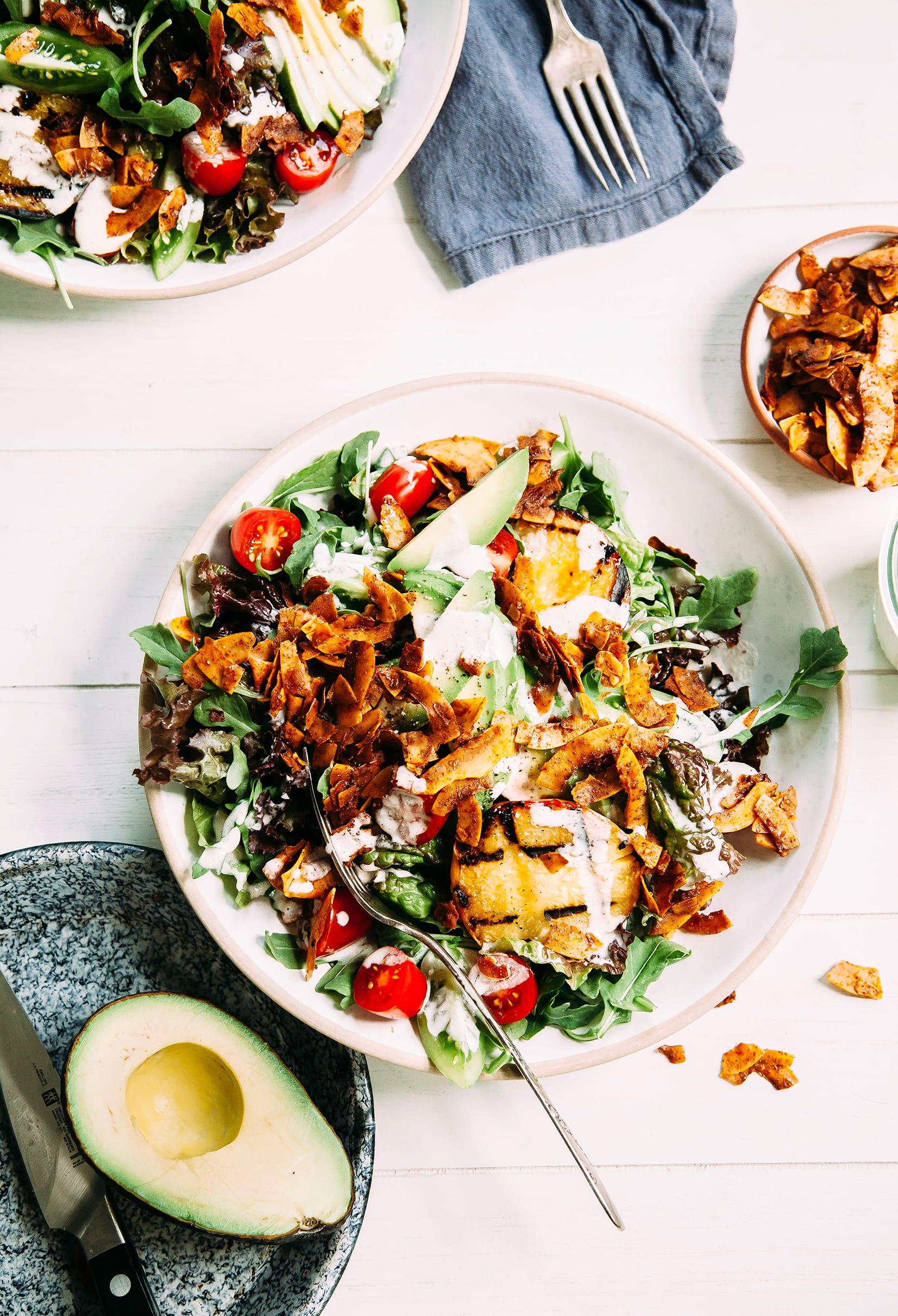 An overhead shot of a vegan BLT salad topped with browned coconut "bacon" bits and a creamy white dressing.
