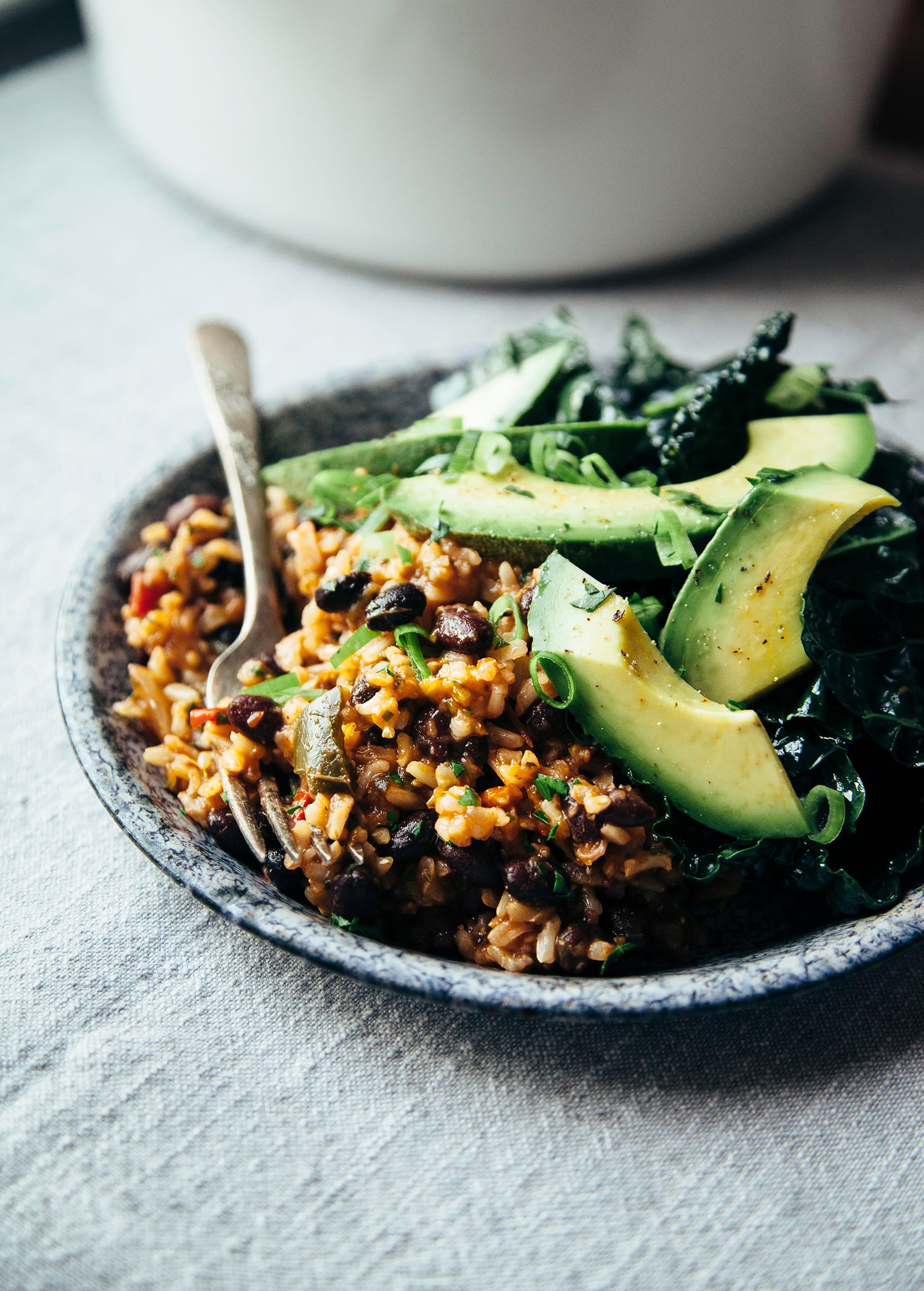 A 3/4 angle shot of spiced black beans and rice with slices of ripe avocado on top.