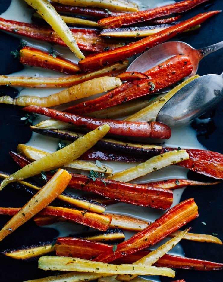 An overhead shot of roasted carrots on top of a creamy sauce.