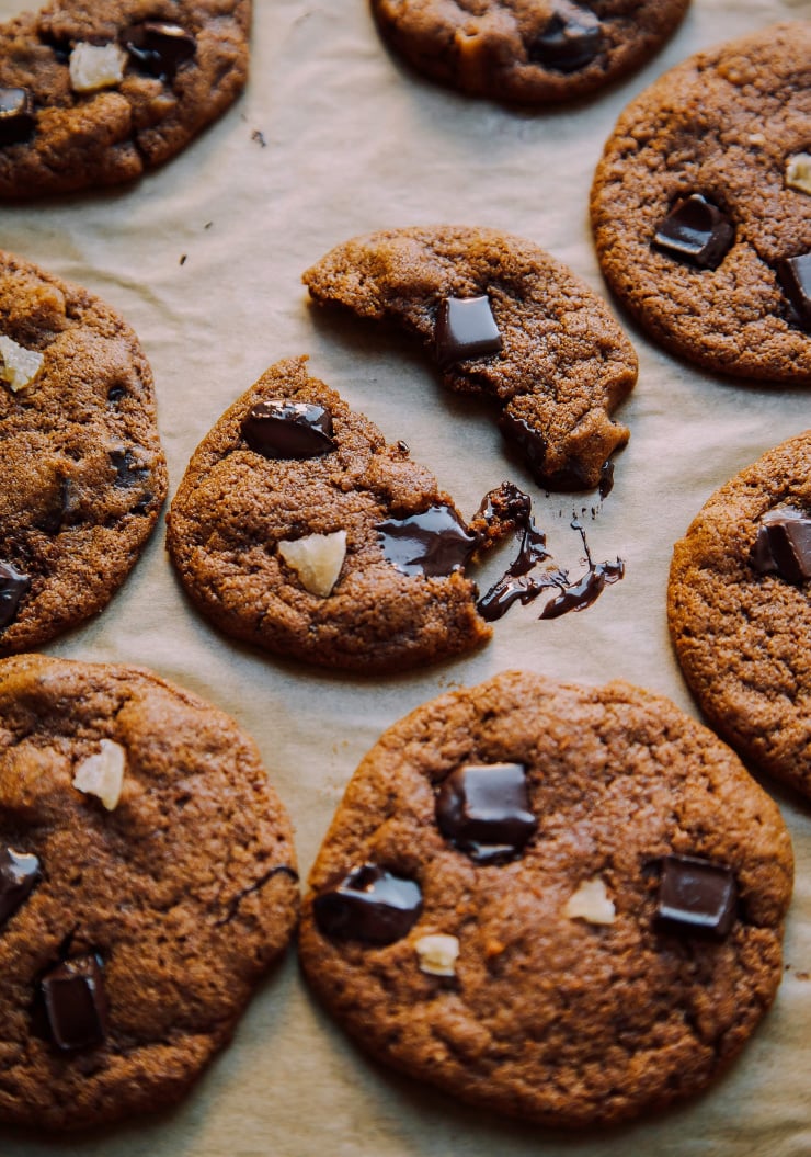 A 3/4 angle shot of vegan chocolate chip ginger cookies with melted pools of chocolate on top.