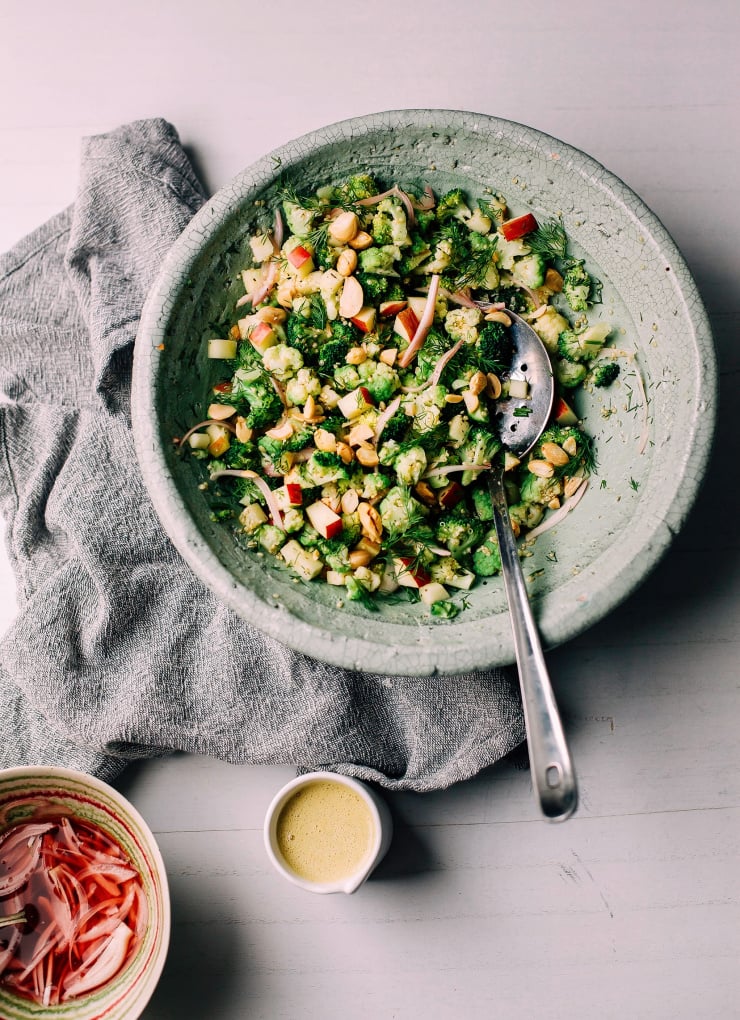 An overhead shot of a broccoli and cauliflower salad in a pale green bowl.