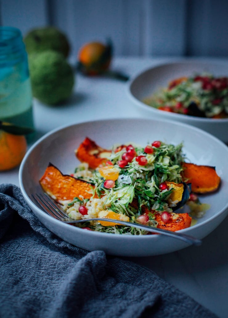 A 3/4 angle shot of roasted squash with a bit of shredded Brussels sprout salad on top in low lighting.