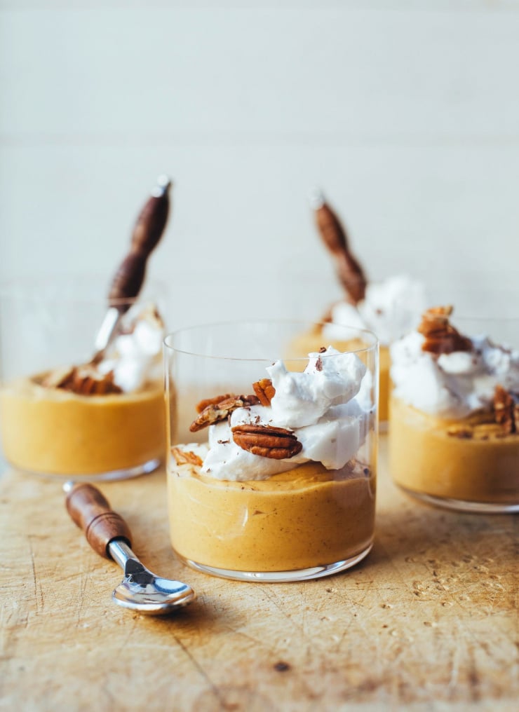 A head on shot of light orange pumpkin mousse in individual glasses.