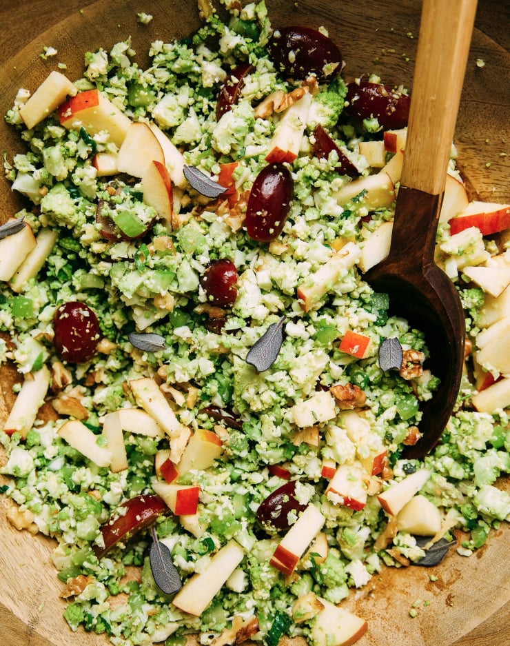 An overhead shot of a finely chopped cauliflower/romanesco I salad with apples and grapes.