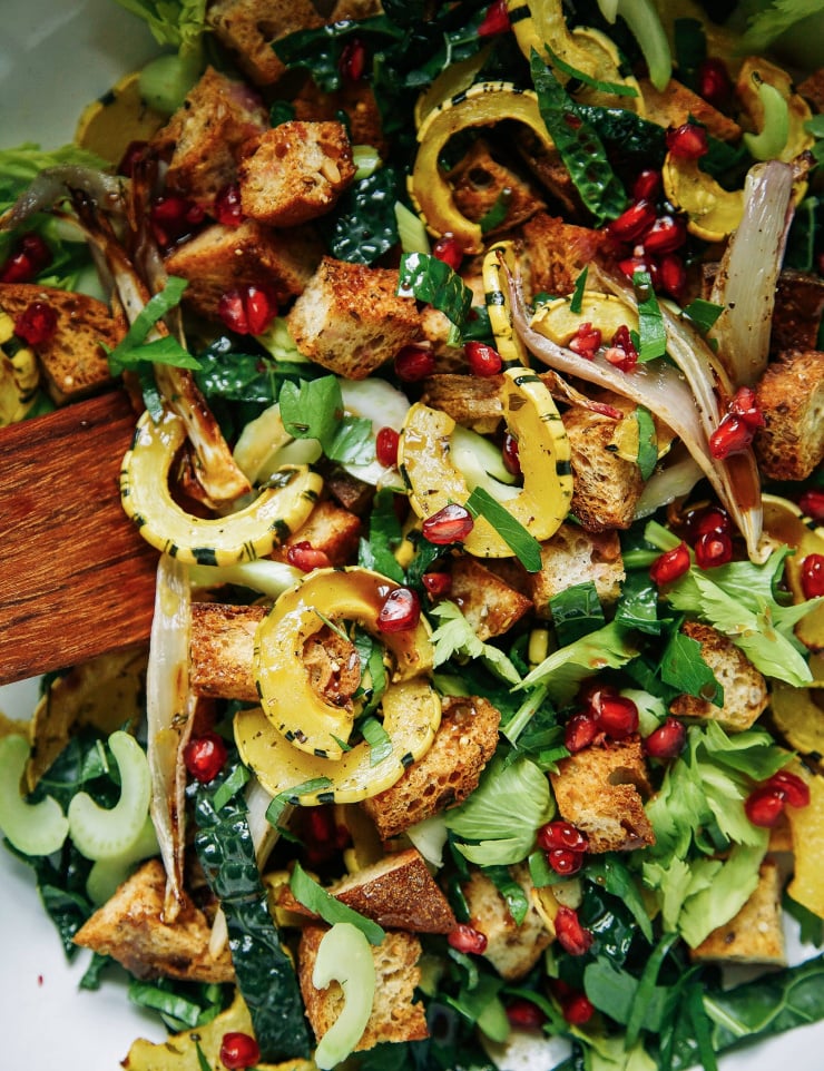 An overhead shot of a roasted squash salad with croutons and lots of chopped herbs. Part of a roundup of vegan holiday recipes