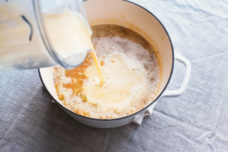 An overhead shot of puréed white bean soup being poured back into the pot.