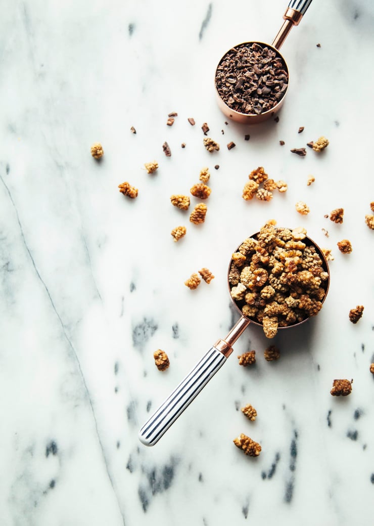 Overhead image shows measuring cups with cacao nibs and mulberries in them.