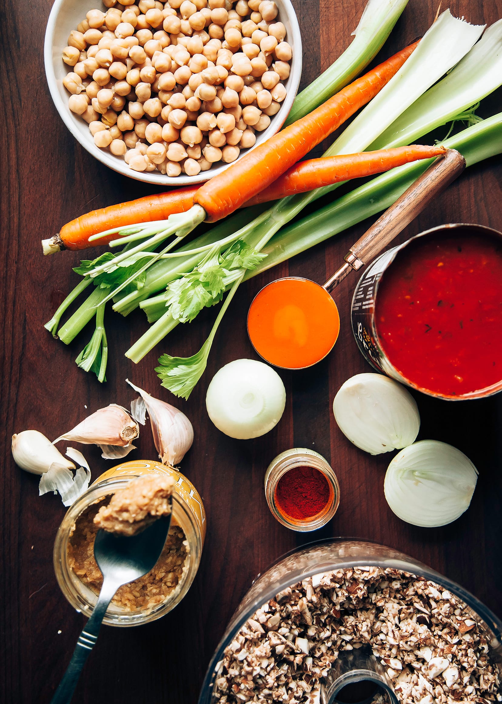 An overhead shot of ingredients for a Buffalo chickpea chili on a dark wood background.