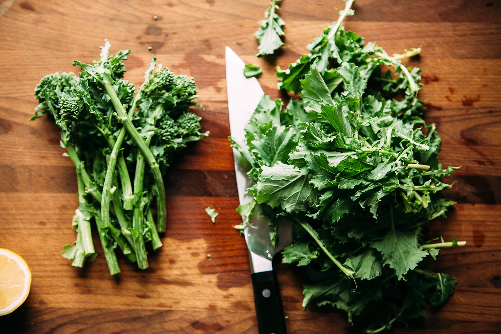 Overhead shot of trimmed broccoli rabe stalks and leaves on a wood cutting board.