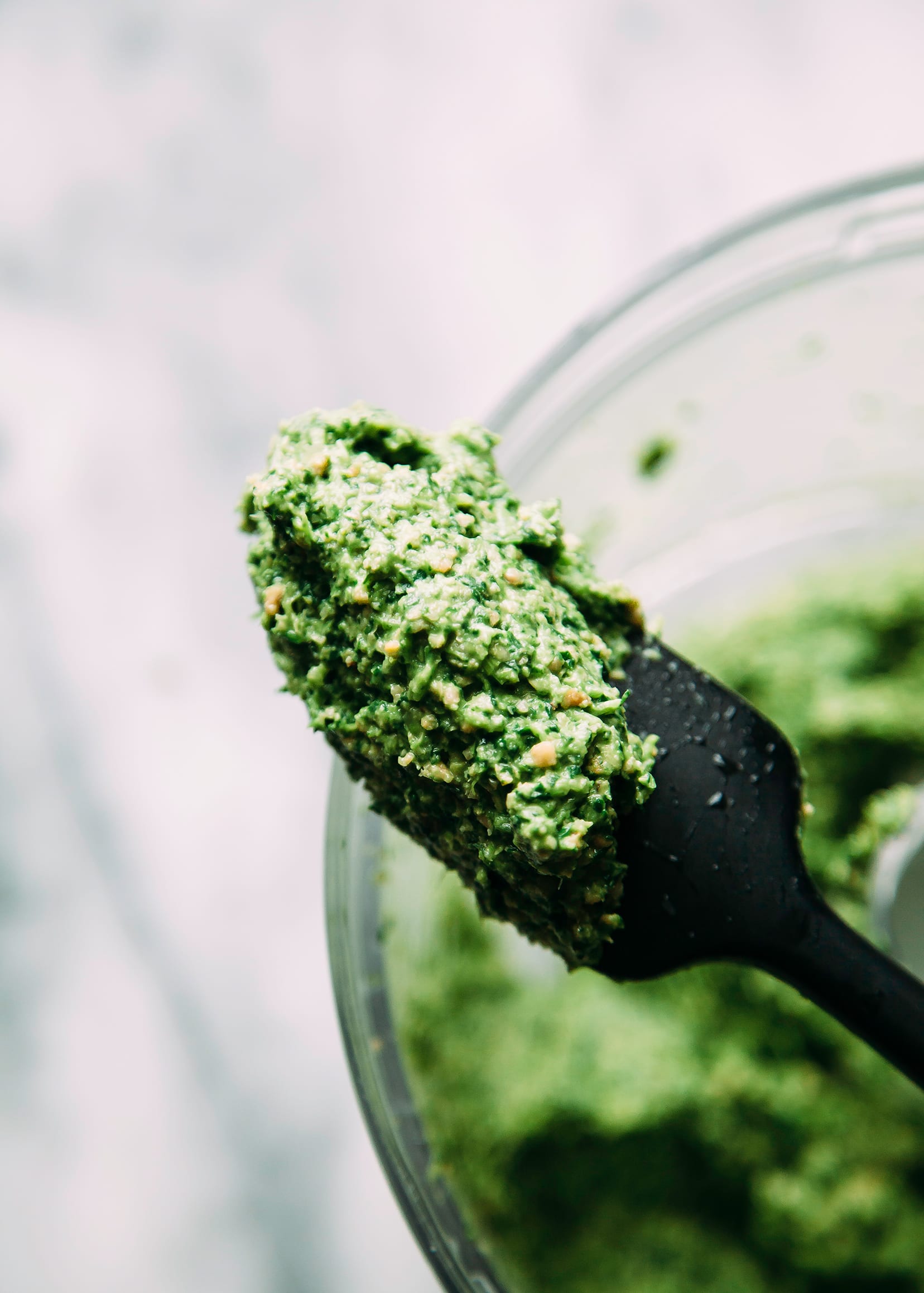 Up close shot of some green pesto on a black spatula.