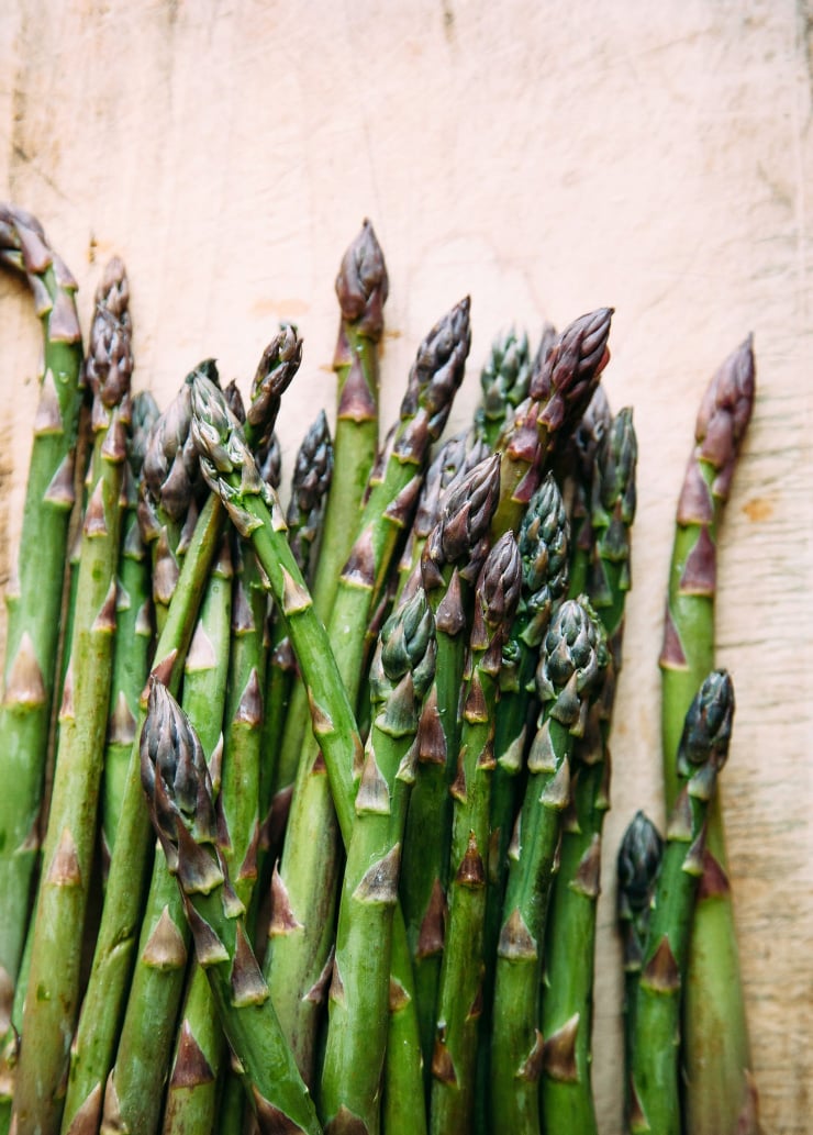 An up close, overhead shot of asparagus spears on a wood background.