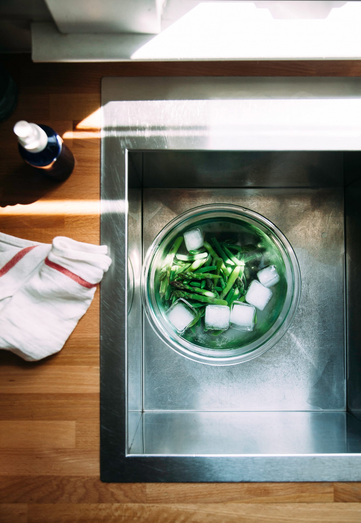 Image shows green vegetables in a bowl of ice water in a sink.