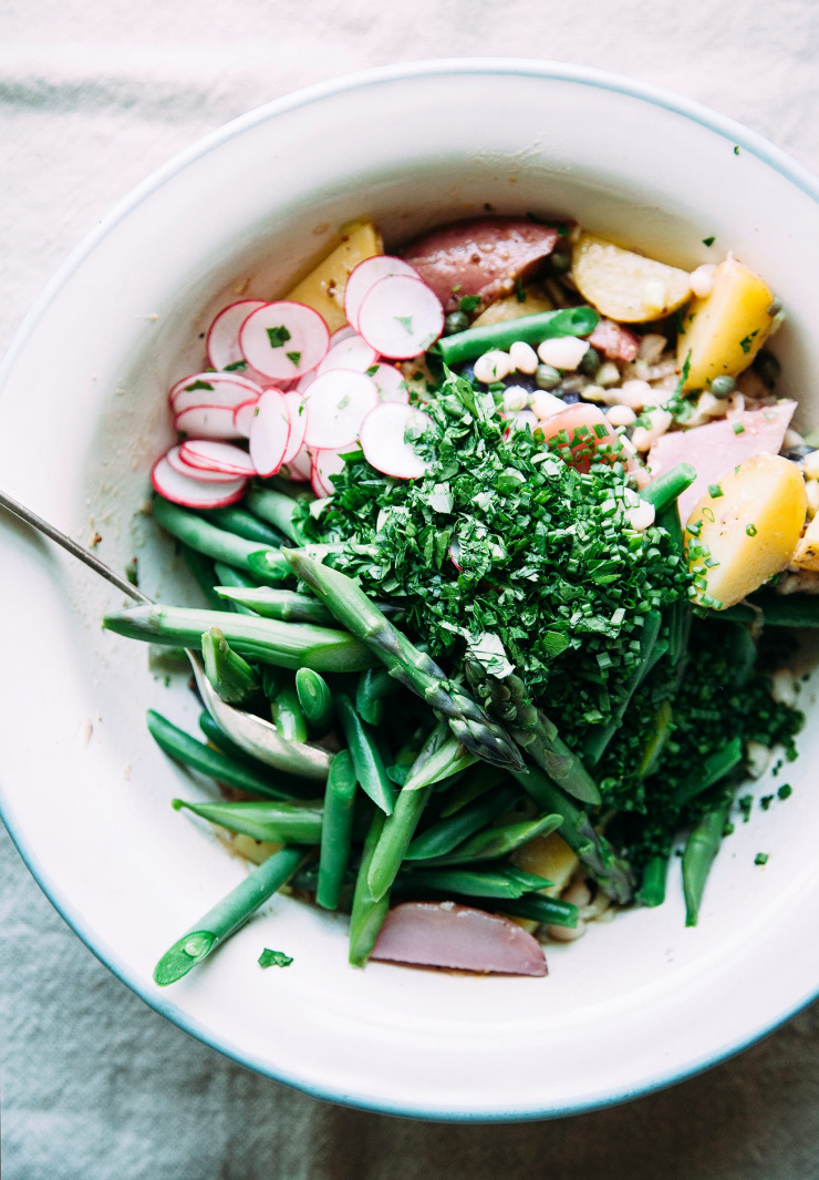Image shows potato salad ingredients in an enamelware bowl, before being mixed together.