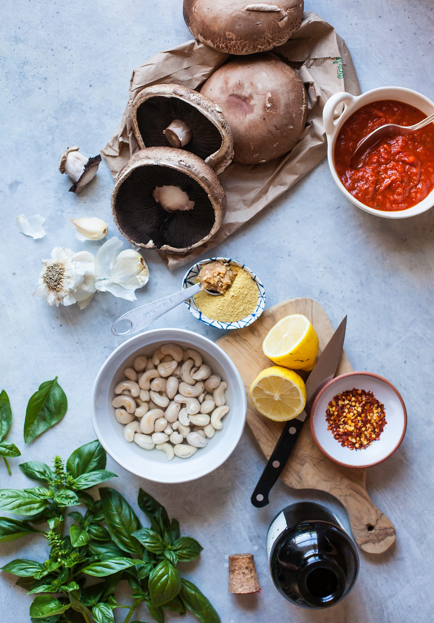 An overhead shot of ingredients for grilled pizza portobellos with lemony cashew ricotta, all on a grey background.