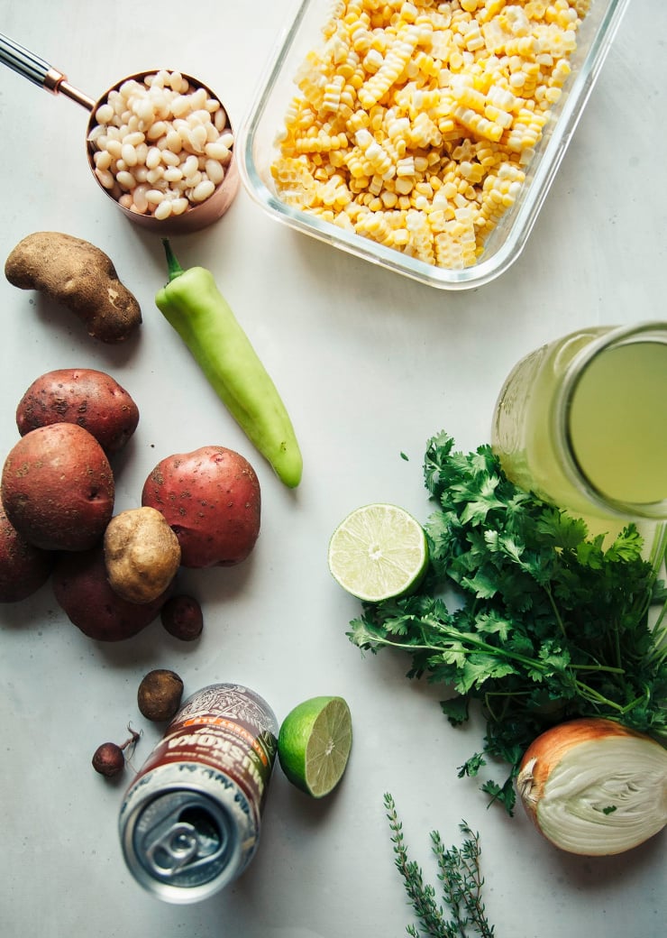 An overhead shot of prep for a vegan corn chowder on a white background.