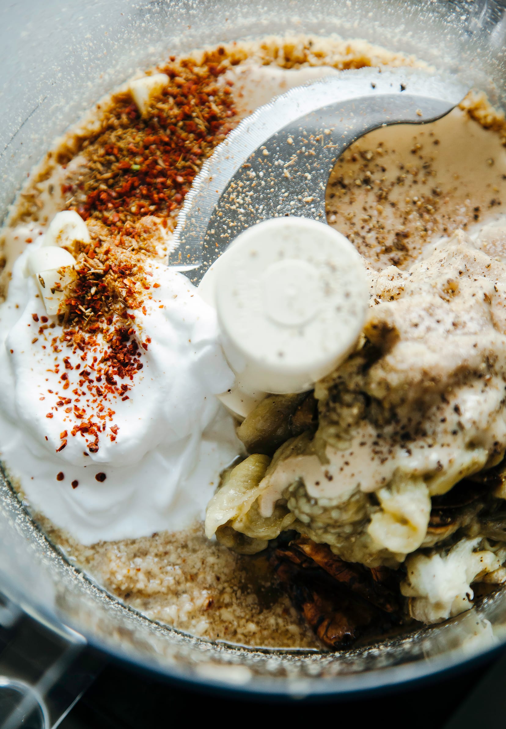 Up close shot of eggplant dip ingredients in a food processor bowl.