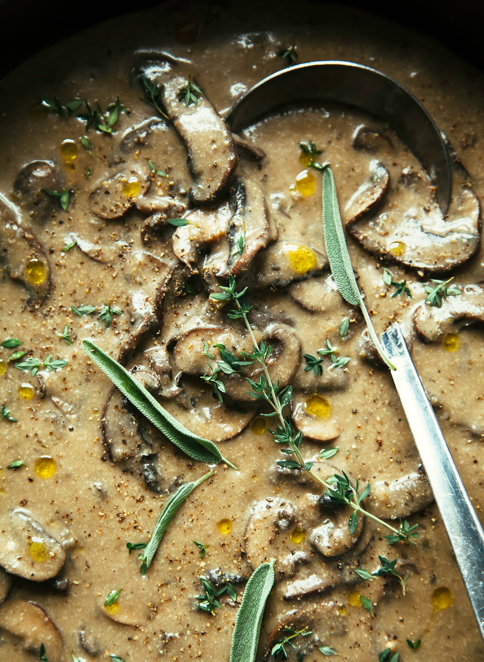 An overhead shot of a creamy mushroom gravy garnished with herbs.