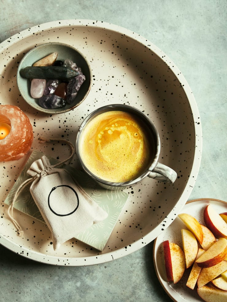 An overhead shot of a creamy, yellow latte in a black speckled white tray.