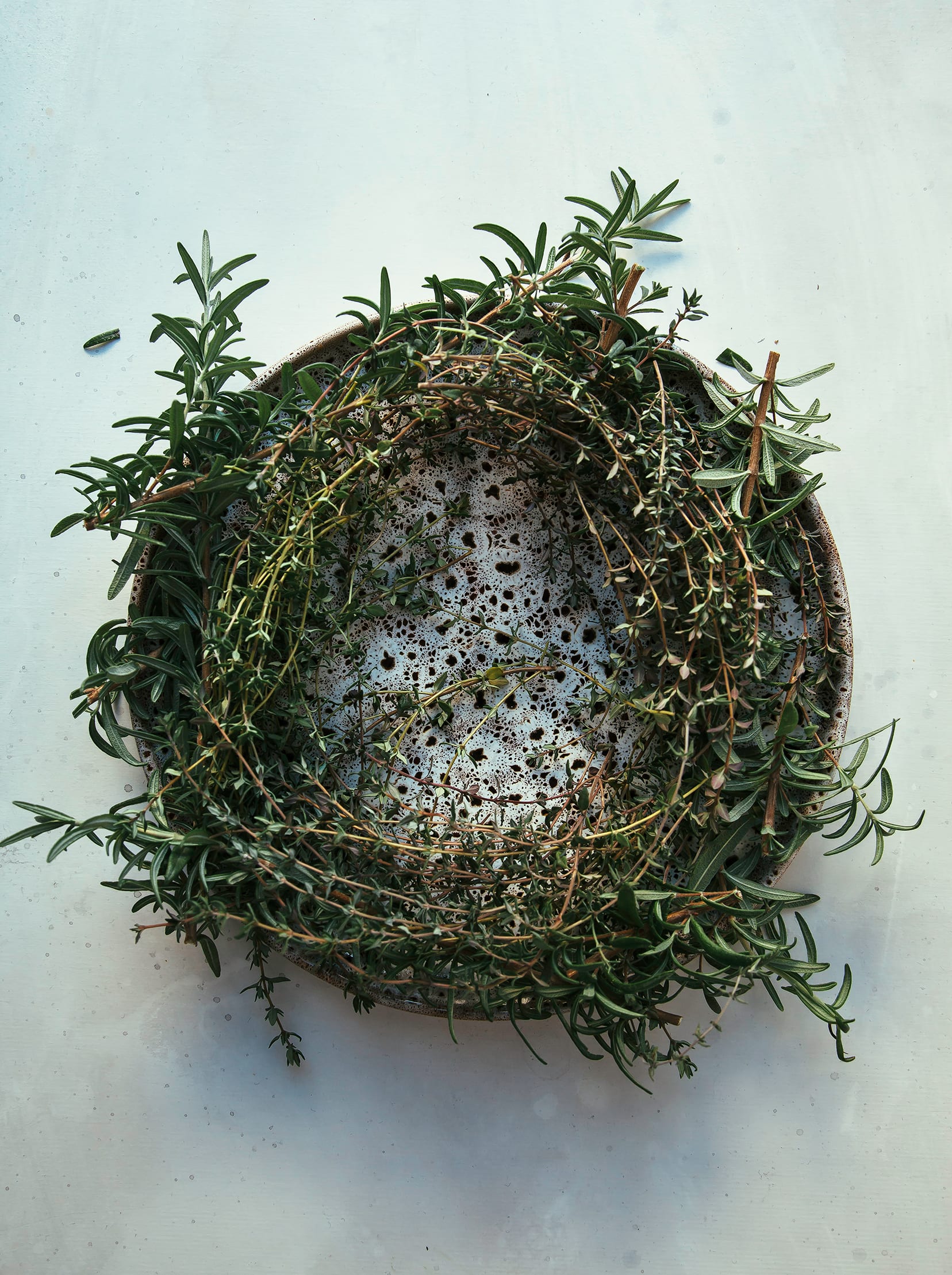 Image shows a “wreath” made out of thyme and rosemary on top of a plate.