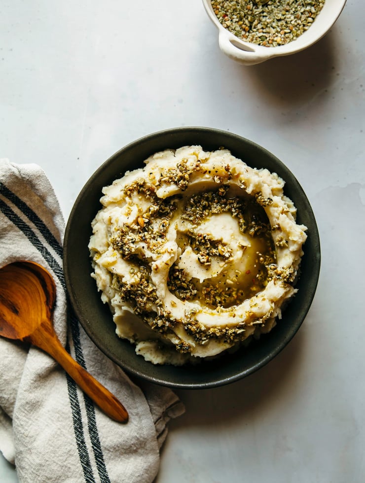 An overhead shot of a creamy vegetable mash with a swirl of olive oil and dukkah on top.