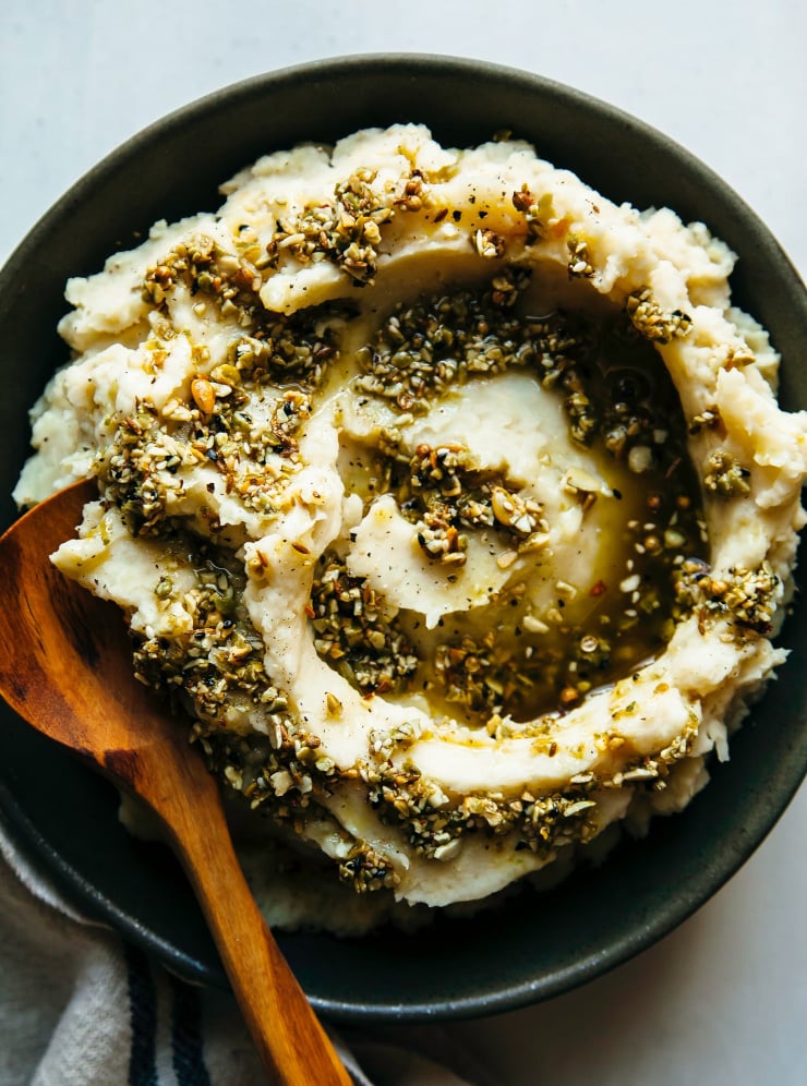 An overhead shot of mashed root vegetables swirled with olive oil and dukkah.