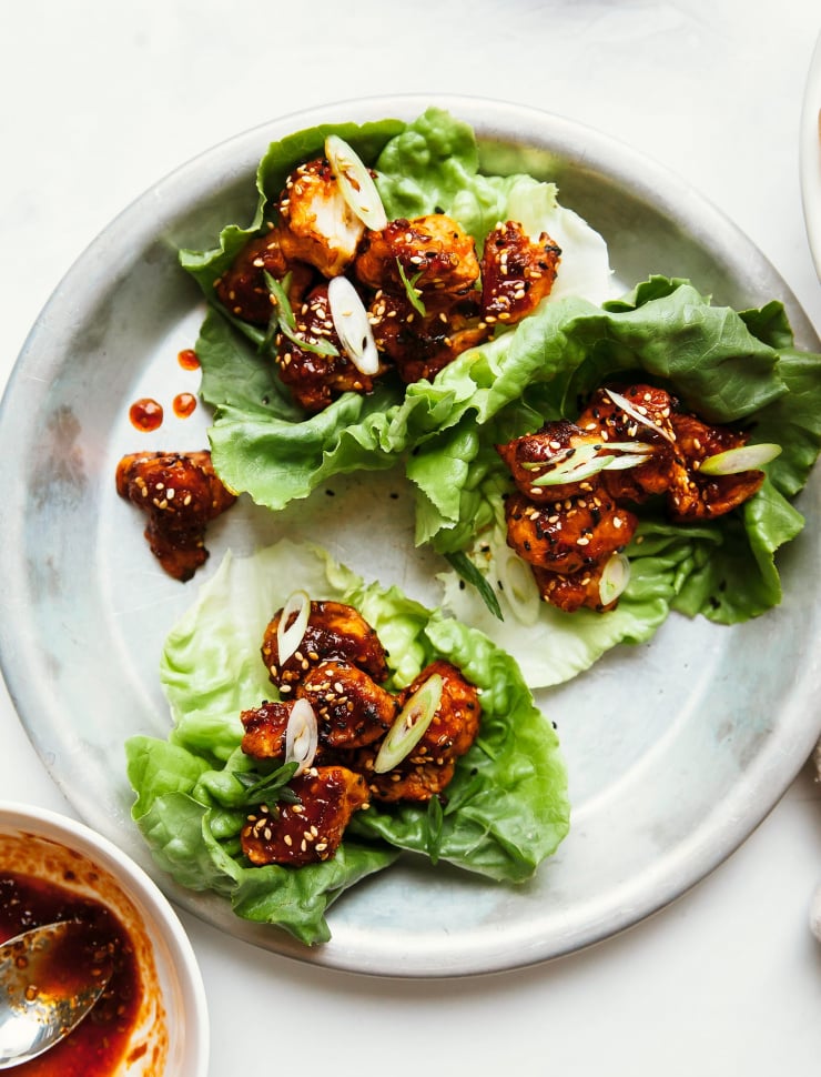 An overhead shot of sticky and crispy sesame cauliflower bites in lettuce wraps.