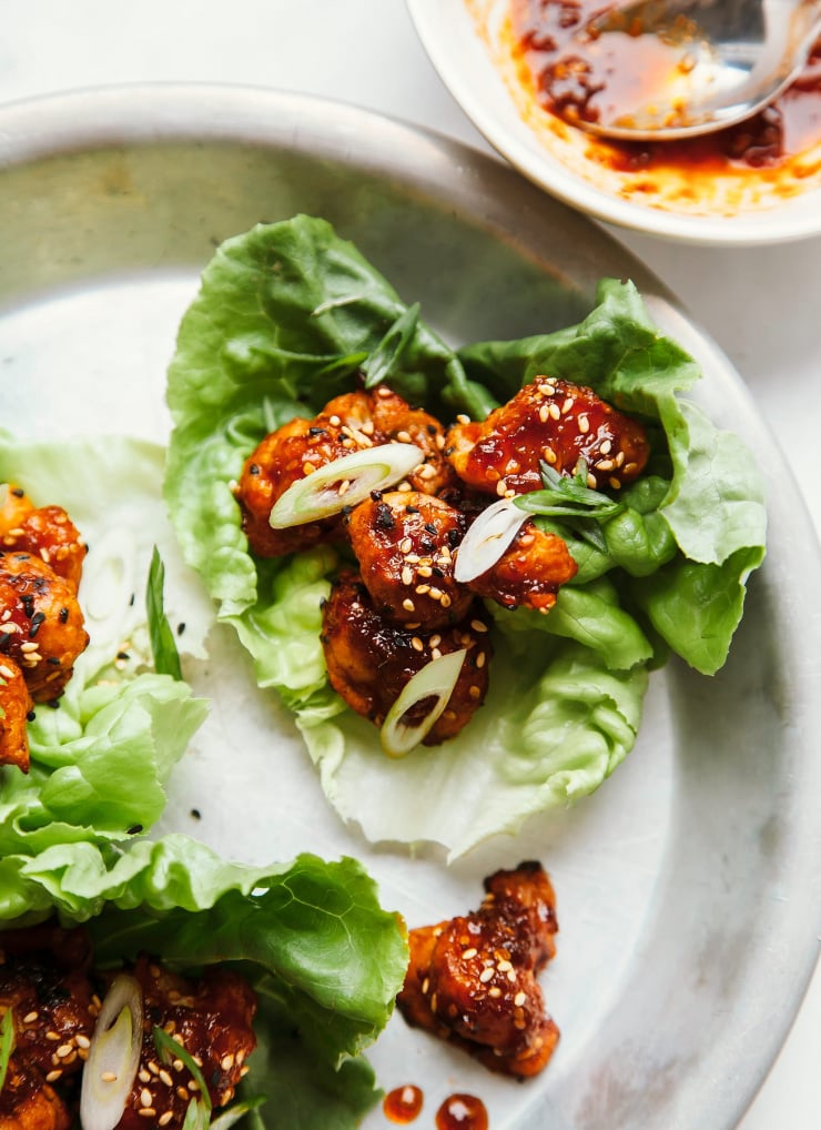An overhead shot of sticky and crispy sesame cauliflower bites in lettuce wraps.