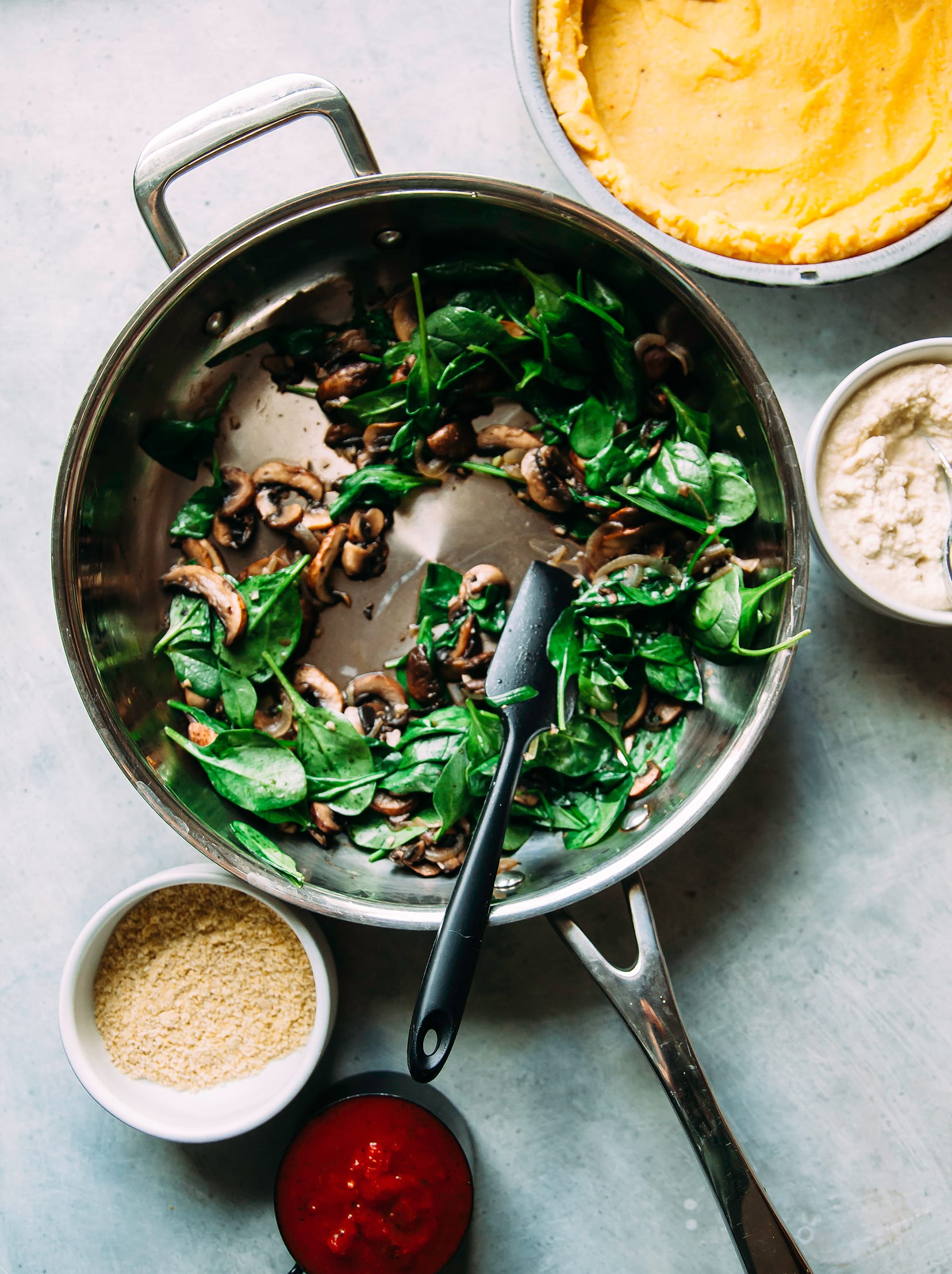 Image shows a sauté pan with cooked mushrooms and spinach.