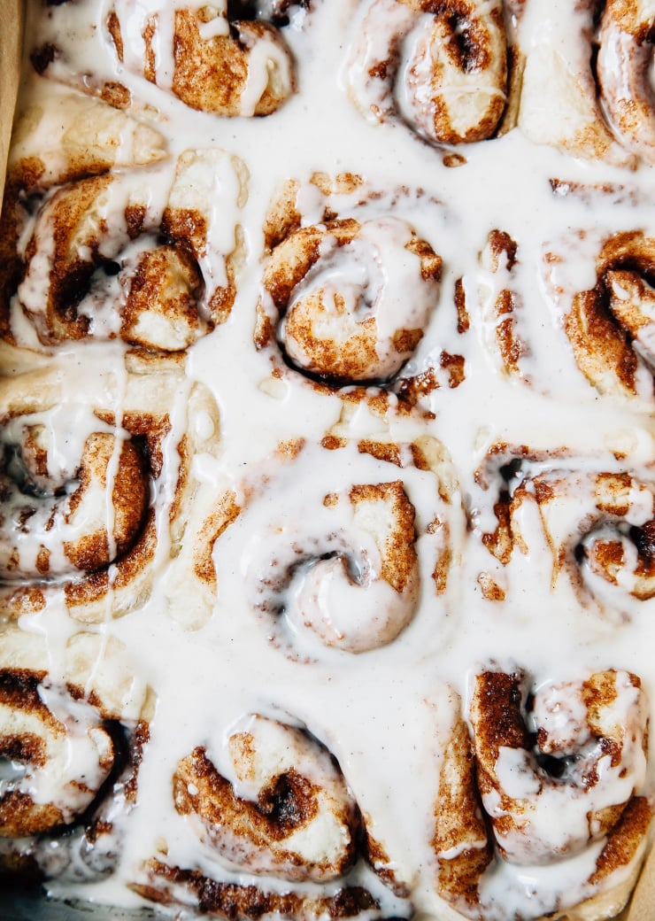 An overhead shot of a pan of vegan cinnamon rolls with icing on top.