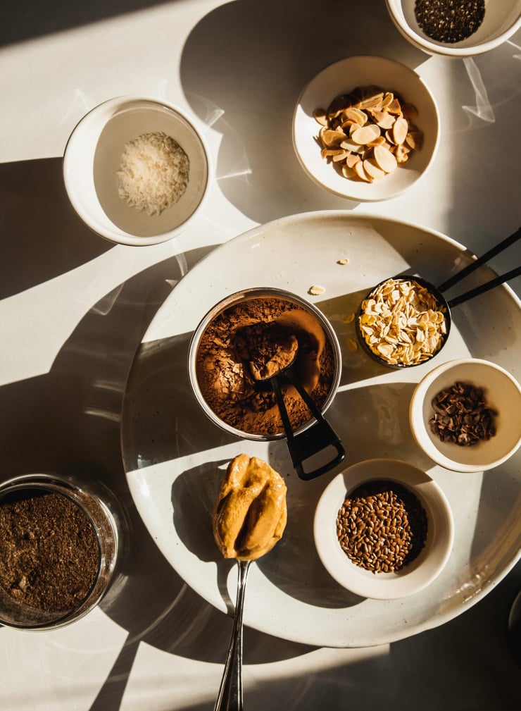 An overhead shot of hearty chocolate oat smoothie ingredients in direct sunlight.
