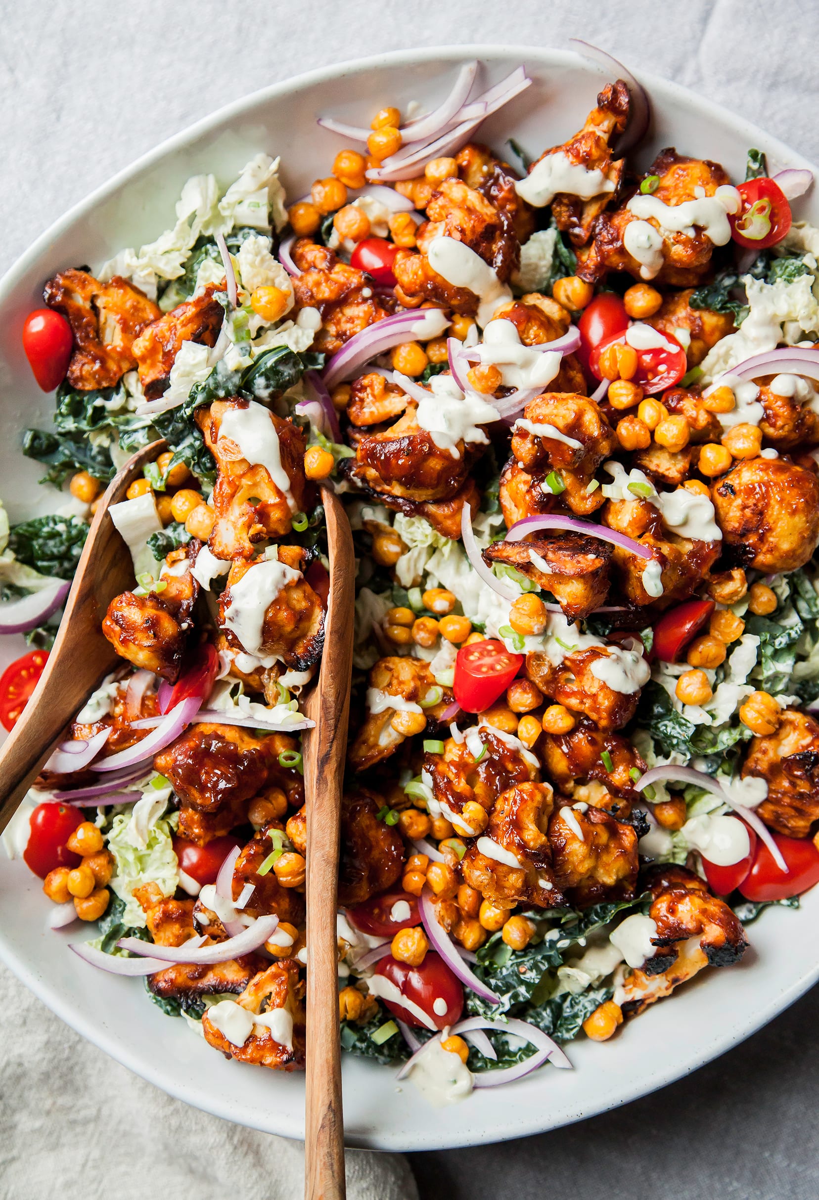 An overhead shot of a Napa cabbage and kale salad topped with BBQ cauliflower, chickpeas, and creamy dressing.