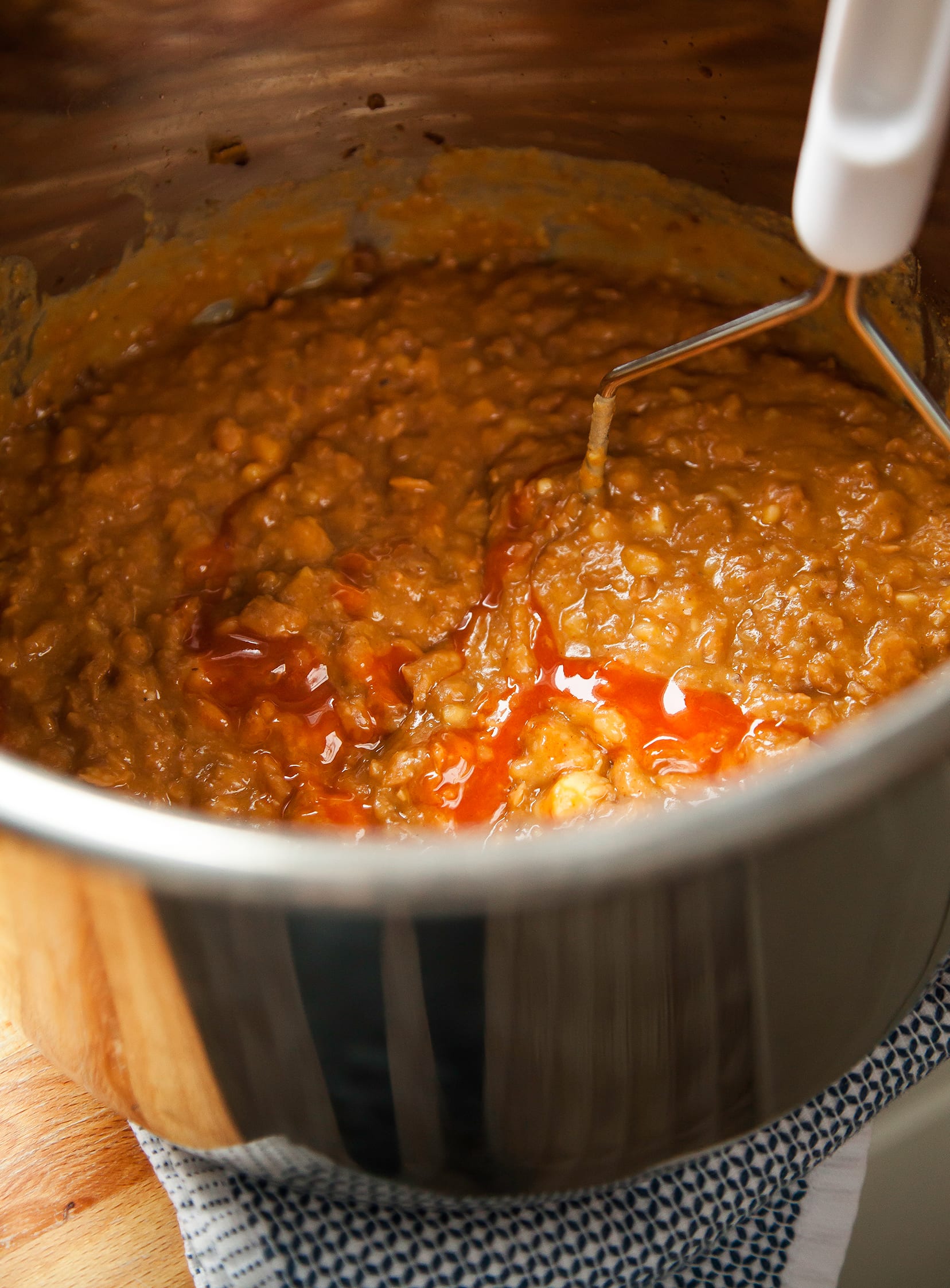 An up close shot of Buffalo refried beans being mashed with a potato masher.