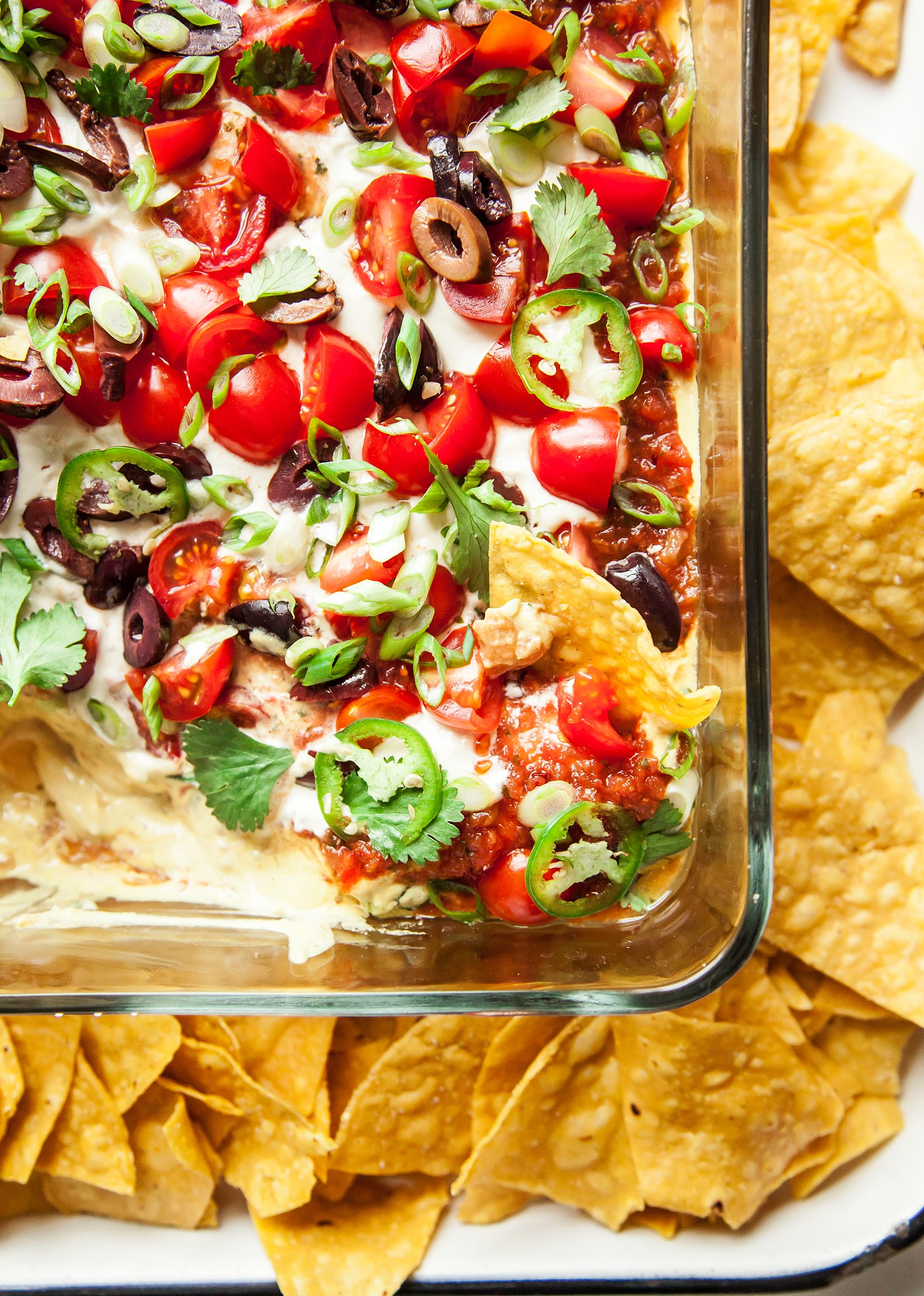 An overhead shot of vegan seven layer dip with garnishes.