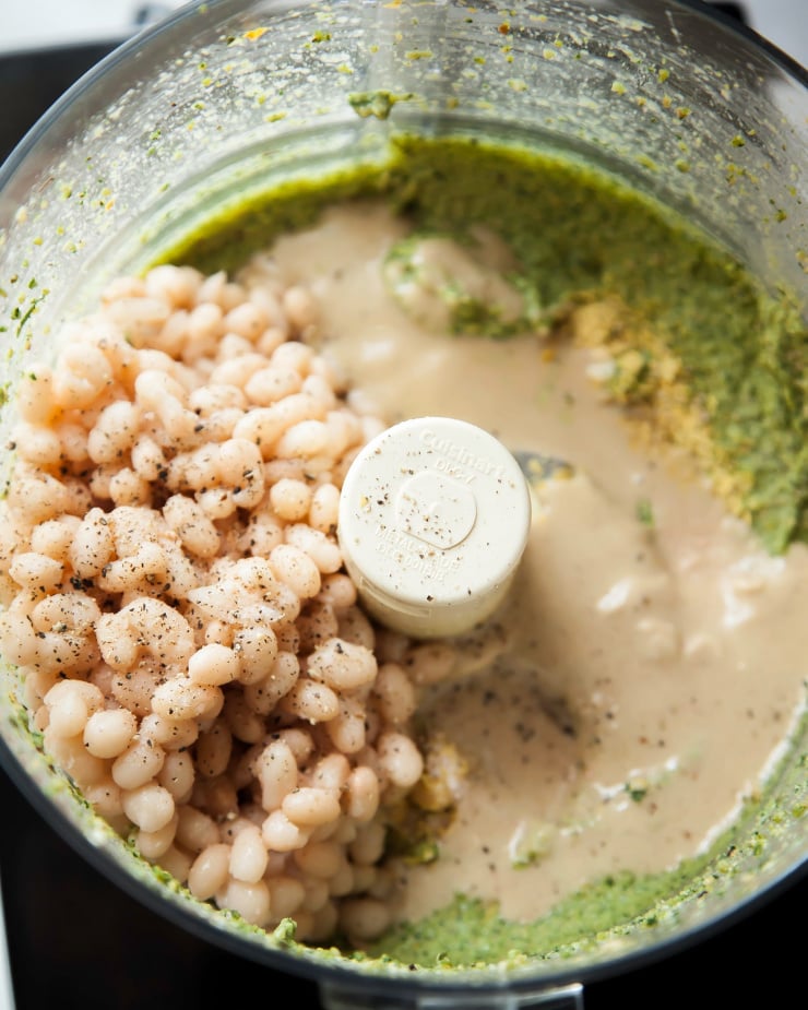 Image shows ingredients for a dip in the bowl of a food processor.