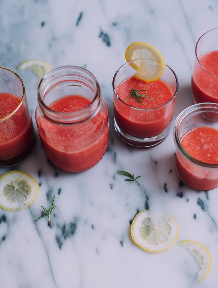 A 3/4 angle of bright pink frozen watermelon add in 5 different, clear glasses. Glasses are filled at the halfway mark and are on top of a marble background.