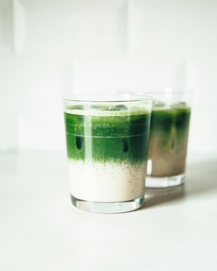 Image shows two glasses with a two-toned beverage against a white background. The bottom half of the beverage is creamy white and the top is bright green.