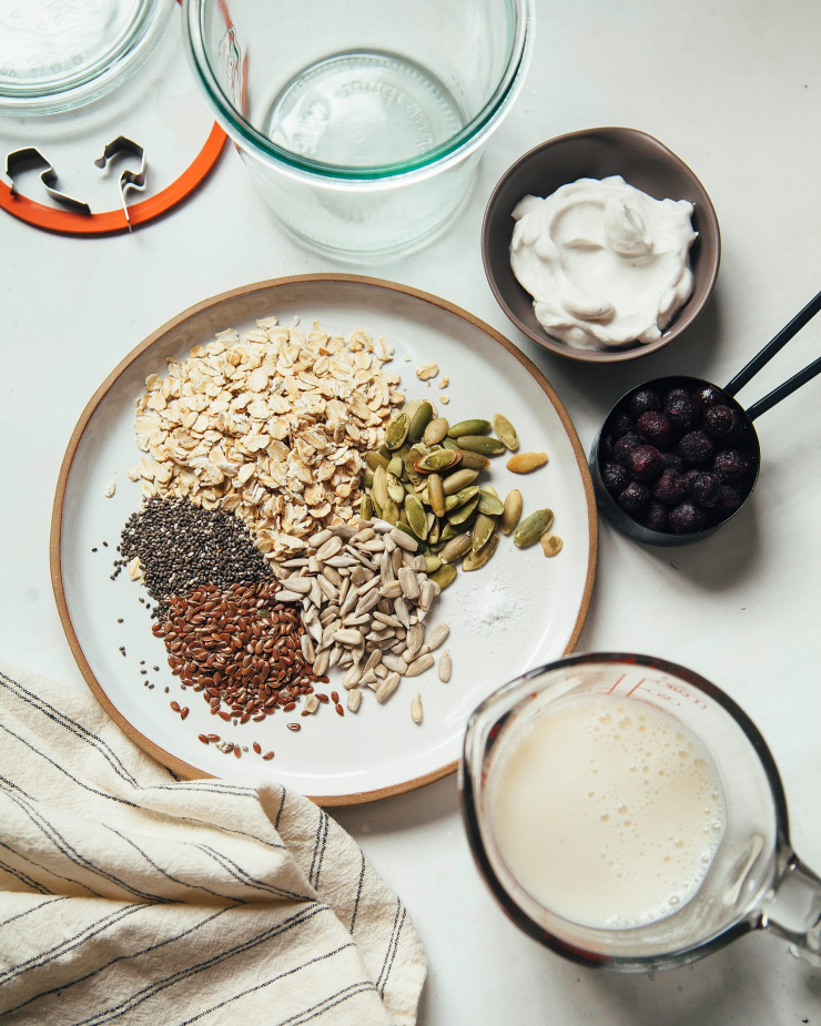 An overhead shot of ingredients for a Bircher muesli on a white background.