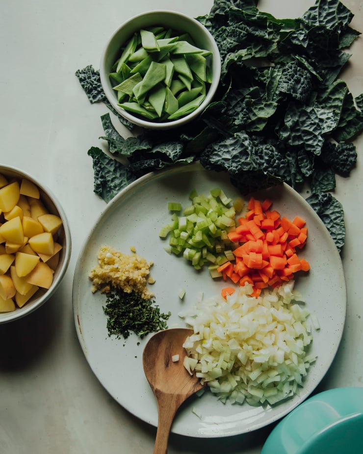 An overhead shot of prepped and chopped vegetables on plates and in bowls.