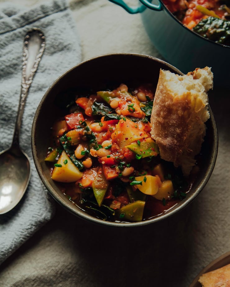 Image shows a bowl of deep red stew with a crust of bread sticking out.