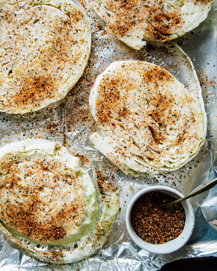 Image shows sliced rounds of cabbage coated in spices.