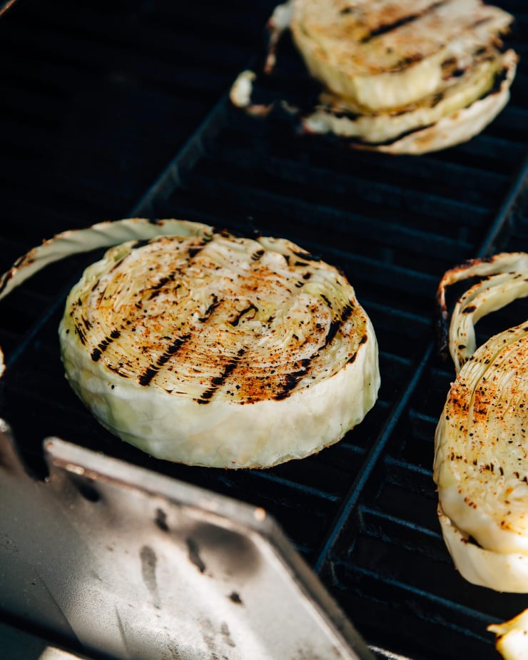Image shows rounds of cabbage on a grill with char marks.