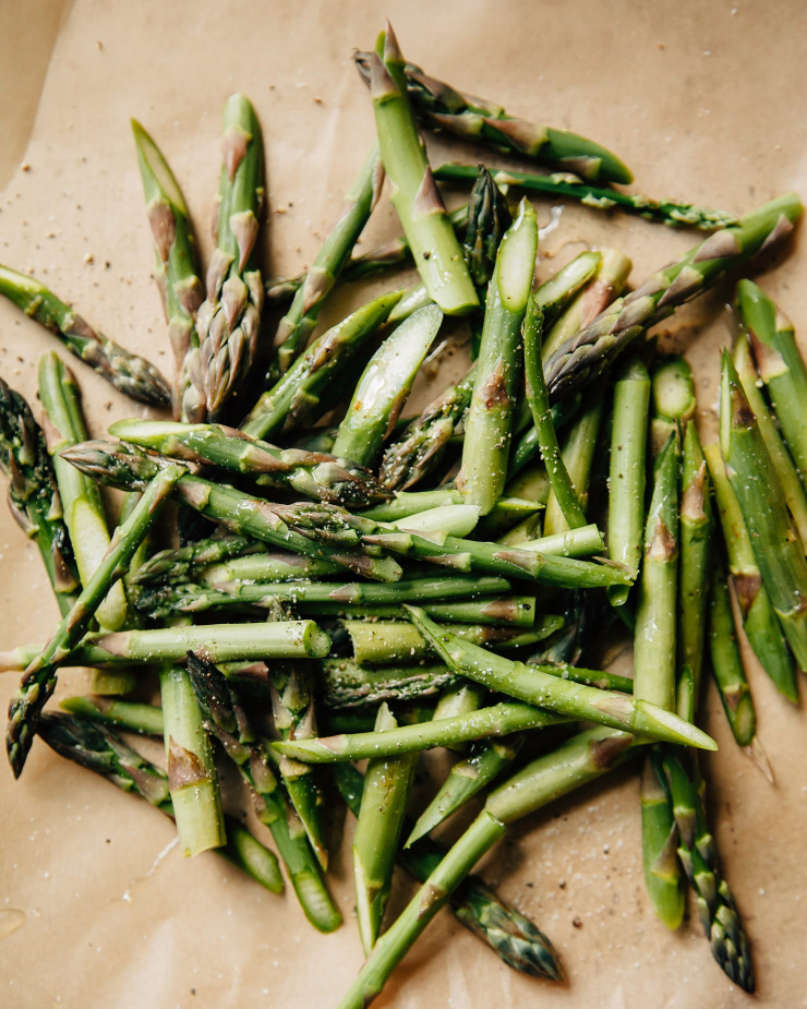 Overhead shot of cut asparagus on top of brown parchment paper, prior to roasting.