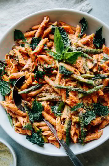 Overhead shot of finished and styled double rosé pasta with asparagus and kale. It is served in a large bowl.