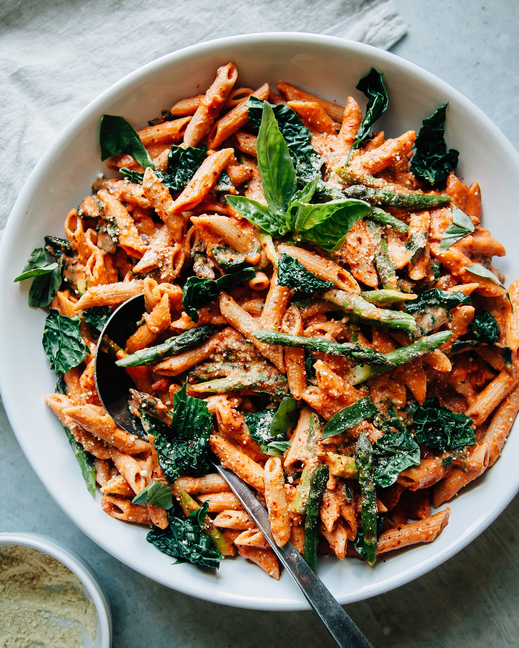 Overhead shot of finished and styled double rosé pasta with asparagus and kale. It is served in a large bowl.